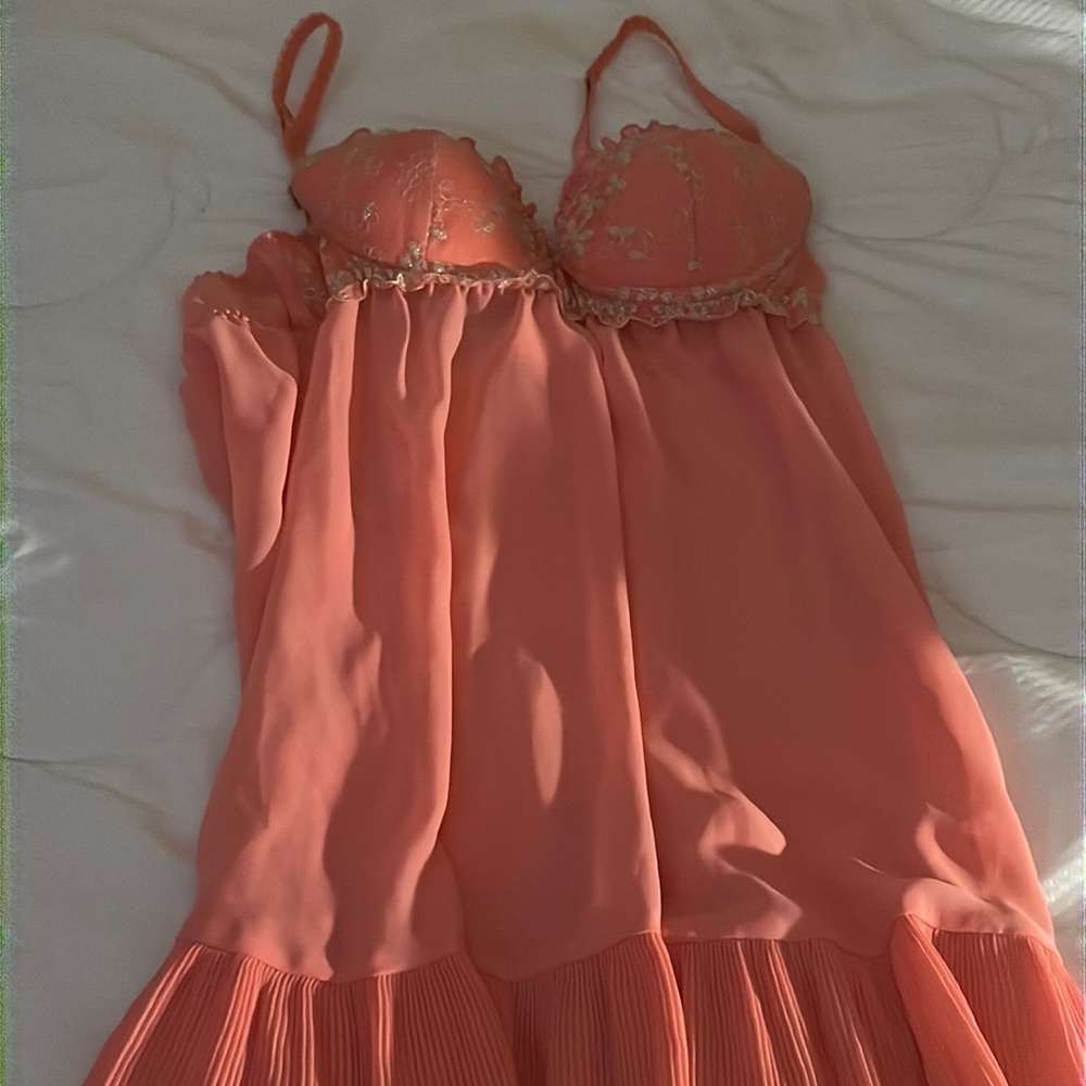 Woman orange sleep wear with gold trimming and ruffle bottom.